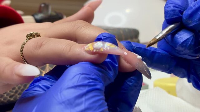 Technician carefully detailing nail art design with precision tools to enhance beauty and style.