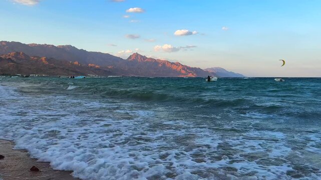 Big waves on Dahab Beach with Kite Surfer on the horizon in Red Sea and Sinai Mountains in Background