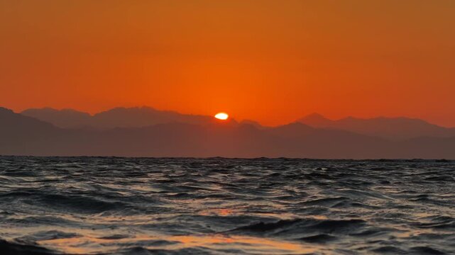 Red Sun Rising over Mountain Range Silhouette across the sea. Beautiful nature landscape
