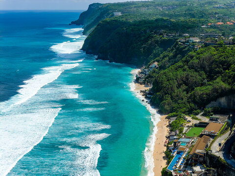 Drone view of beautiful tropical coastline, white sand beach, rolling waves and cliffs