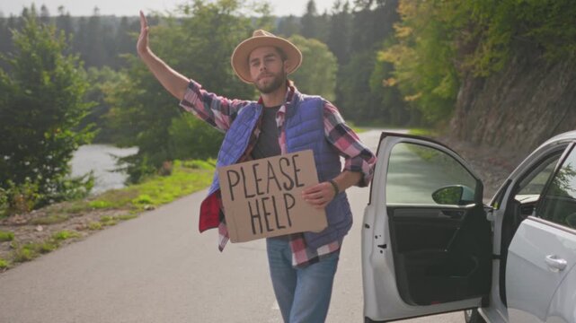 Friendly roadside gesture, Cheerful hitchhiker with please help sign on picturesque rural landscape background