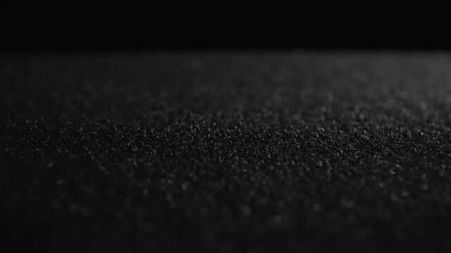 Close-up of dark grainy textured surface with shallow depth