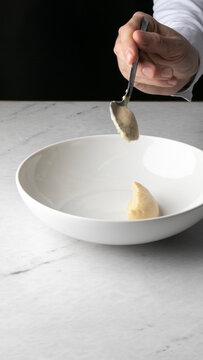 A delicate scoop of espuma descends into a porcelain bowl, evoking culinary art and the whimsical spirit of La Tomatina