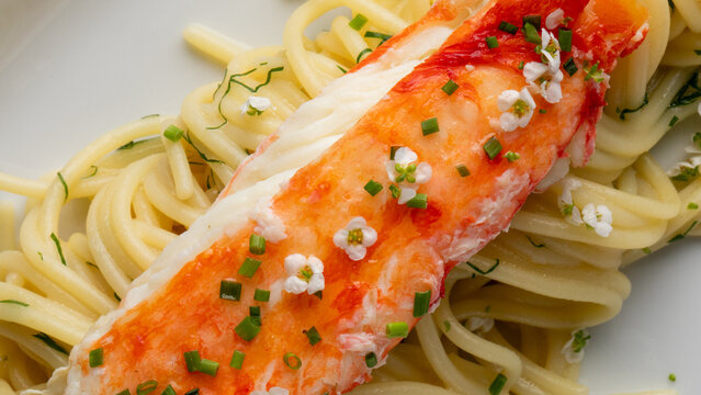 Elegant crab leg crowns al dente noodles with floral sprinkles, invoking Obon festivities and ephemeral cherry blossom viewing