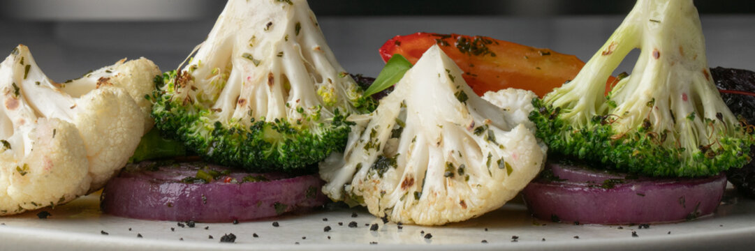Grilled cauliflower and broccoli florets dance atop red onion rings, exuding umami bliss, capturing Veganuary vitality and Feast of St Fiacre whimsy