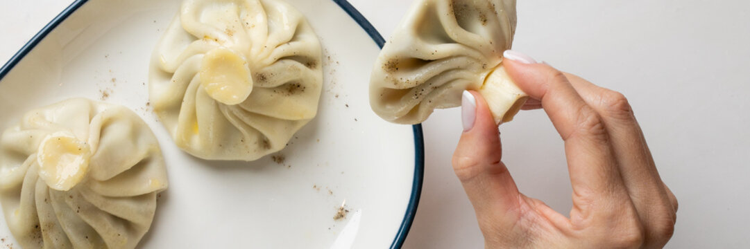 A hand gently lifts a steaming khinkali, evoking Georgian feast traditions and warm gatherings on International Dumpling Day