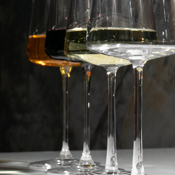 Four elegant wine glasses shimmer with amber, gold, and ivory hues, perfect for Sommelier Day and Bacchanalia festivities