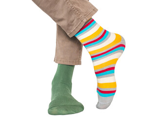 Fototapeta premium Man wearing mismatched colorful striped and green socks and light brown pants without shoes. Casual fashion, individuality and self-expression concept. Studio shot on isolated background, closeup