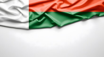 Obraz premium The national flag of Madagascar, featuring its distinctive red, green, and white colors, draped on a clean white background with ample copy space.