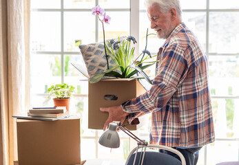 Active senior man involved in moving house moving cardboard boxes, concept of relocation,...