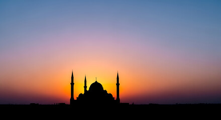Naklejka premium Serene mosque silhouette at vibrant sunset with colorful sky