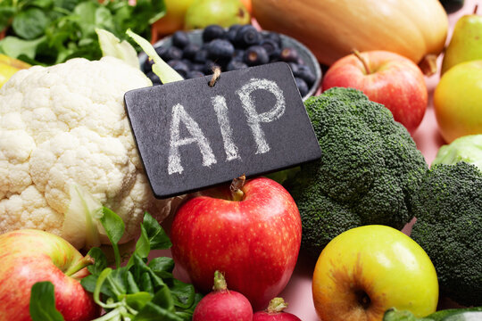 Flat lay of fresh AIP friendly fruits and vegetables on pink