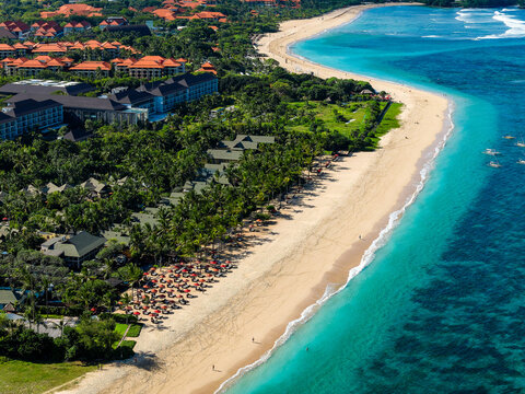 Aerial drone view of a beautiful tropical beach resort with white sand and blue ocean