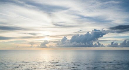Sunset over a calm ocean with scattered clouds reflecting on the water surface