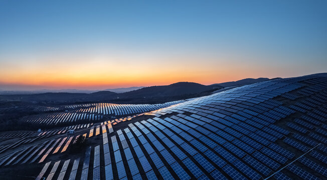 Aerial view of solar farm on mountain slopes during twilight