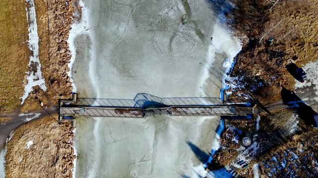 Cinematic drone pedestal shot of a wooden bridge over the frozen Aurajoki river in Turku, Finland.