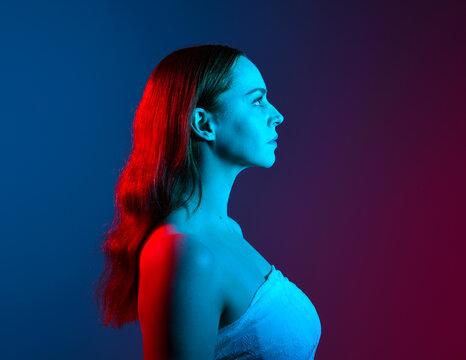 Close up studio portrait of female model face with creative neon studio lighting and slow shutter speed creating colourful blue and red 3d surreal effect.