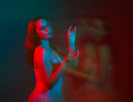 Close up studio portrait of female model face with creative neon studio lighting and slow shutter speed creating colourful blue and red 3d surreal effect.