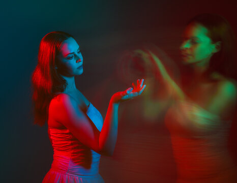 Close up studio portrait of female model face with creative neon studio lighting and slow shutter speed creating colourful blue and red 3d surreal effect.