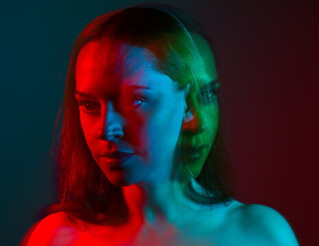 Close up studio portrait of female model face with creative neon studio lighting and slow shutter speed creating colourful blue and red 3d surreal effect.