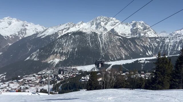 Aerial view of Courchevel ski resort by winter with ski lifts over the town and Mont Blanc in the background