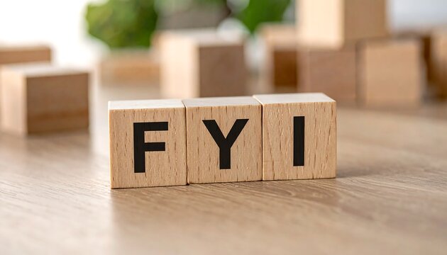 Wooden blocks spelling "FYI" on a textured light brown surface, others scattered in the blurry background