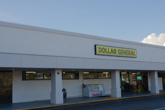 Exterior view of a Dollar General storefront in a suburban strip mall with prominent yellow signage. Editorial Use Only March 6, 2026 St. Petersburg, FL USA. shopping carts and a quiet parking area, e