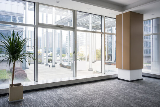 Modern office space with floor-to-ceiling windows, potted plant, and partition column