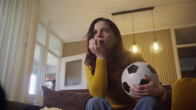 Emotional woman watching soccer on TV at home celebrating team goal