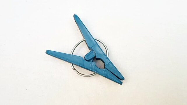 A blue plastic clothes pin or clothes peg for house isolated rotating on the white background, Laundry clip, top view