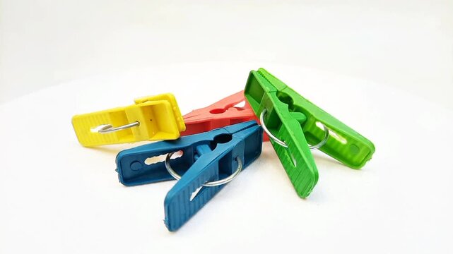 Clothes pins, four multi color plastic laundry clips or clothes pegs for house rotating on the white background