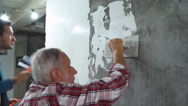 Father and Son Plastering Wall During Home Renovation	
