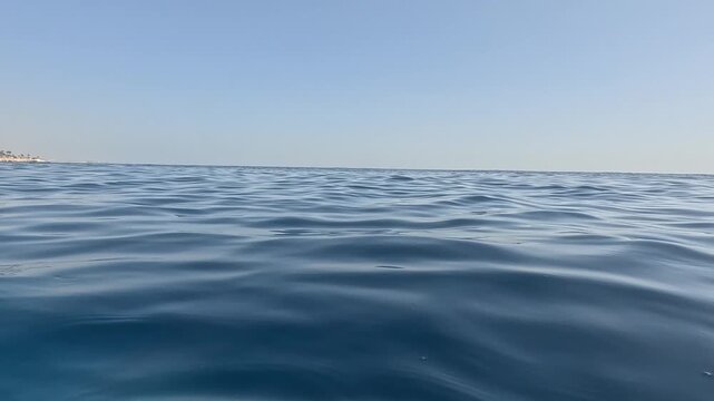 Open sea water waves in Sinai Peninsula. Calm blue ocean surface with floating buoy and boat in distance. Serene marine landscape during sunny summer day trip.