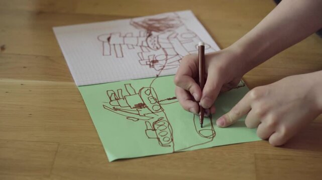 Child finishing vehicle drawing on green paper, hands adding final pencil strokes over layered sketches, playful transport scene, creative