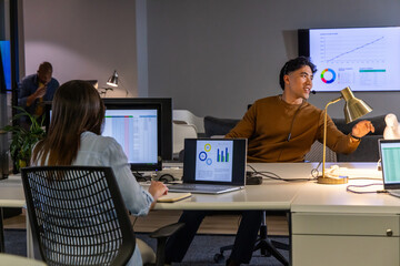 Diverse coworkers with Asian man gesturing at desk, colleague taking notes in notebook, copy space