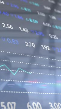 Vertical video: Cam scrolling glass display updating numbers, teal line spiking, finance monitoring