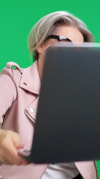 Smiling businesswoman comically hitting her head with a laptop