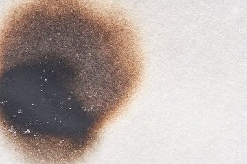 Close-up of burn mark on white paper showing texture and gradients in brown and black.
