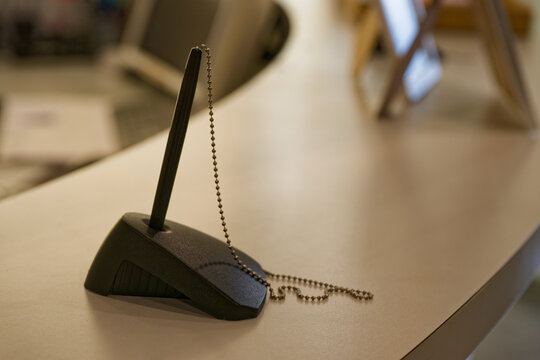 Reception counter with chained pen and stand for sign in office lobby.