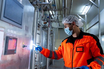 Workers in safety gear inside a factory are checking equipment and machinery to store chemicals and...