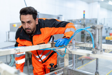 Workers in safety gear inside a factory check equipment and products on production and transportation lines in a closely monitored, state-of-the-art food processing plant.