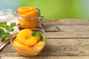Pickled peaches and mint leaves on wooden table, closeup. Space for text © New Africa