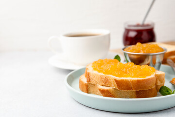 Toasts with sweet jam, mint and tea on light grey table, closeup. Space for text