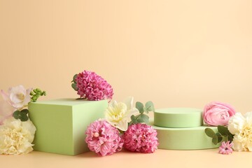 Naklejka premium Empty podiums and spring flowers on beige background, closeup. Mockup for design