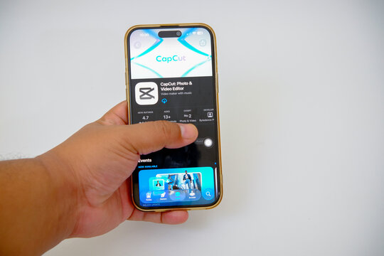 Smartphone Displaying the Capcut Video Editing Application Within an App Store Interface Held by a Persons Hand with a Clean White Background
