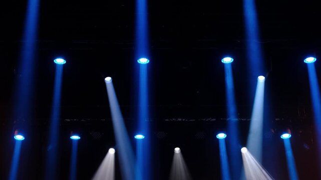 Blue moving lights illuminate stage with theatrical effects in slow motion, professional lighting setup for concerts shows nightclubs and audiovisual events