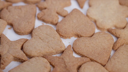 Close up homemade heart and star cookies on white surface, warm golden brown tones, crisp edges, subtle sugar dusting, rustic arrangement filling frame, cozy bakery mood