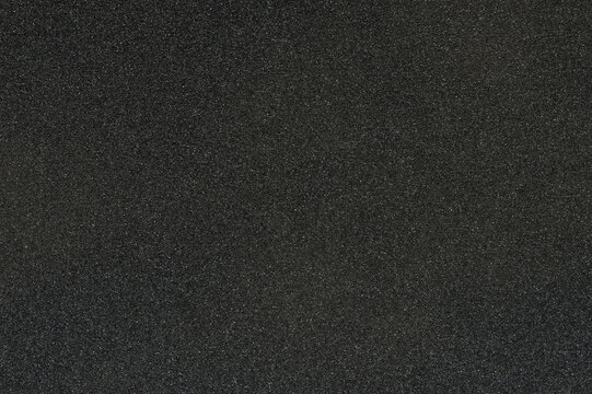 Black sandpaper texture with rough surface showing fine grain details clearly