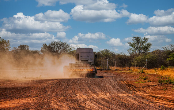 Heavy transport truck driving on dirt road kick up dust cloud rural construction site infrastructure