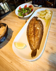 Sole. Platter with grilled sole and boiled potatoes. There is also a platter with salad. This dish was served in Galicia.